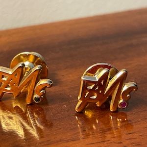 GOLD. Pair of initials in gold. Gold brooches with ruby and sapphire.