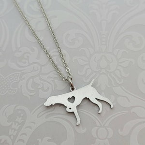 May include: A silver necklace with a pendant shaped like a German Shorthaired Pointer dog with a heart cut out in the center. The dog is standing with its head turned to the side.