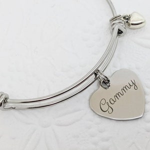 May include: A silver expandable bracelet with a heart charm engraved with the word "Gammy".