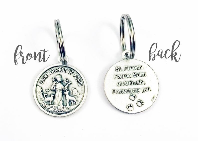 May include: Silver key chain with a round charm featuring Saint Francis of Assisi holding a bird and two dogs. The back of the charm reads "St. Francis Patron Saint of Animals, Protect my pet." with three paw prints.