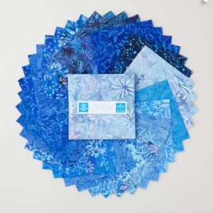 May include: A collection of blue fabric squares arranged in a circular pattern. The fabrics feature various shades of blue with floral and abstract patterns. A central square bundle displays the text "Cloud 9 Fabrics".