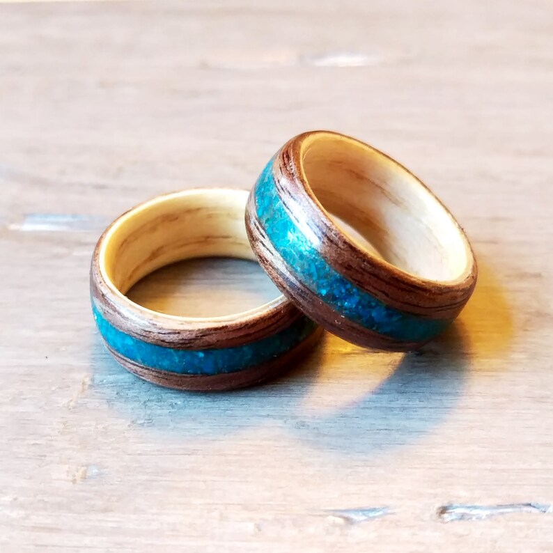 May include: Two wooden rings with a turquoise inlay. The rings are made of dark wood and light wood.