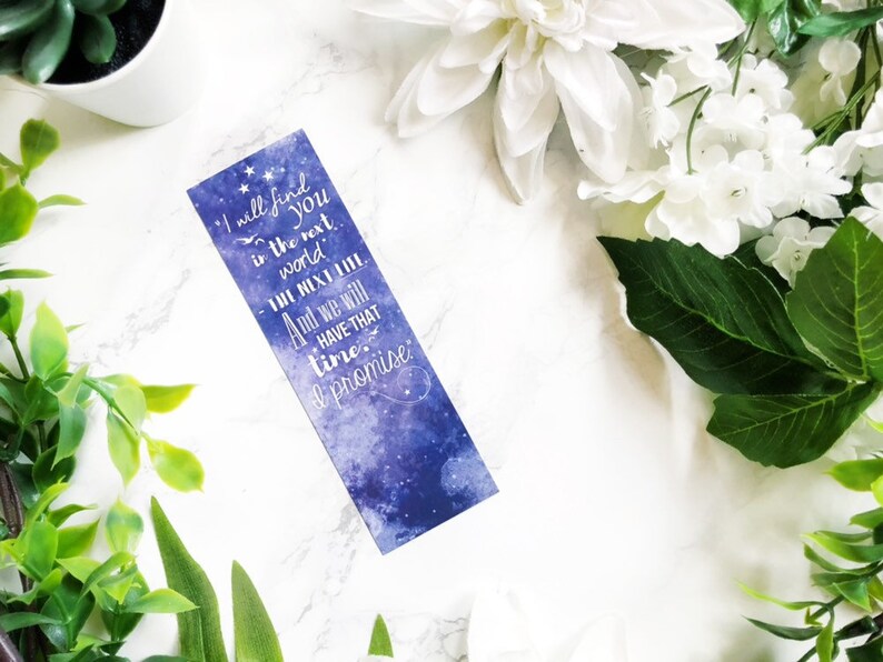 May include: A blue and purple galaxy-themed bookmark with the text "I will find you in the next world. The next life. And we will have that time. I promise."