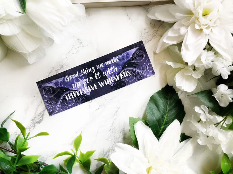 May include: Purple and black bookmark with a quote that reads "Good thing we make up for it with impressive wingspans."