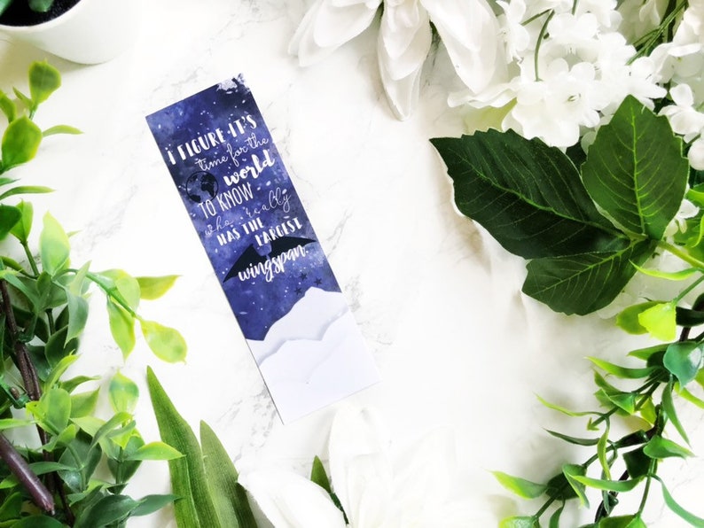 May include: A blue and white bookmark with a quote about the world and a bat with a large wingspan. The quote reads "I figure it's time for the world to know who really has the largest wingspan."