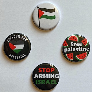 以下が含まれることがあります： 政治的なメッセージが書かれた4つの丸いボタン。1つのボタンにはパレスチナの国旗、別のボタンにはハート型の国旗のデザインで「Freedom for Palestine」と書かれています。3つ目はスイカのスライスで「free palestine」、最後は「STOP ARMING ISRAEL」と書かれています。