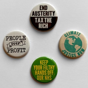 May include: Four circular pin badges with activist slogans. One says "END AUSTERITY TAX THE RICH", another says "PEOPLE over PROFIT", a third says "CLIMATE JUSTICE NOW", and the last says "KEEP YOUR FILTHY HANDS OFF OUR NHS".