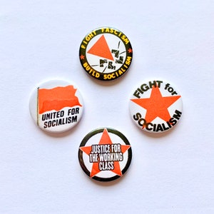 May include: Four round buttons with red and black designs. The buttons feature slogans about fighting fascism and building socialism. The slogans include "Fight Fascism Build Socialism", "United for Socialism", "Fight for Socialism", and "Justice for the Working Class".