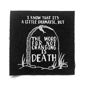Pode incluir: Patch quadrado preto com texto bordado branco e design de lápide. O texto diz: "EU SEI QUE É UM POUCO DRAMÁTICO, MAS A PALAVRA PARA NÃO MUDAR É MORTE".