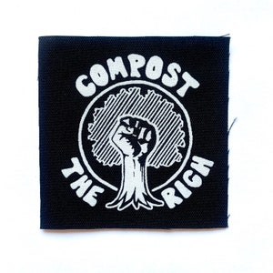 May include: Black square patch with white text and graphic. The text reads "COMPOST THE RICH" around a circular design featuring a tree trunk with a raised fist. The patch is likely for clothing or accessories.