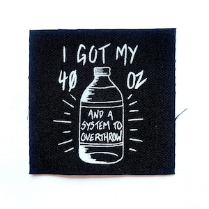 May include: Black square patch with white text and illustration. The text reads "I GOT MY 40 OZ AND A SYSTEM TO OVERTHROW" with a drawing of a bottle. The patch is made of fabric.