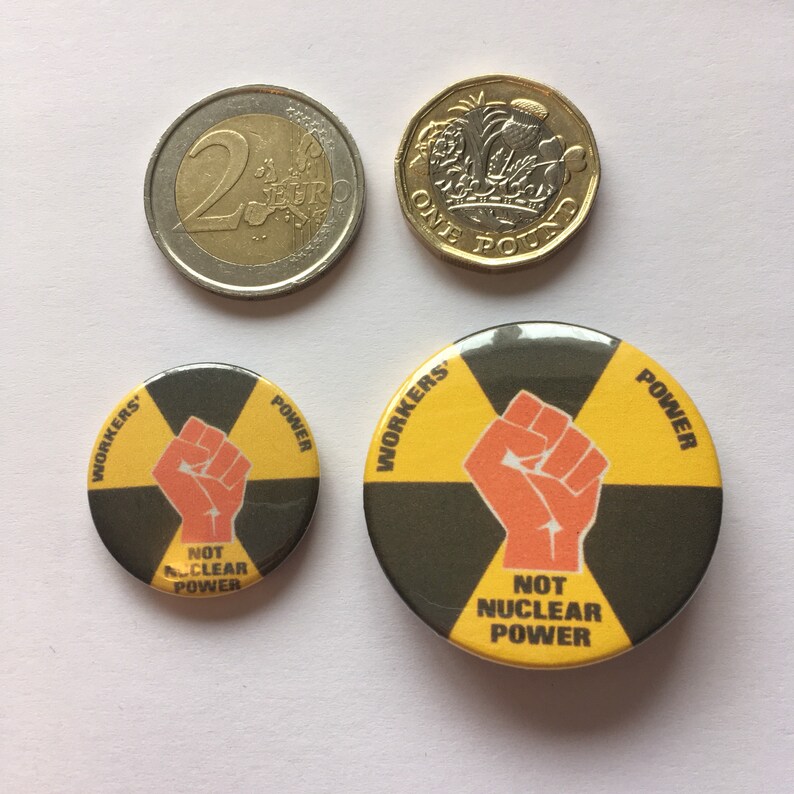 Pu&ograve; includere: Due badge a bottone gialli e neri con il testo "Workers Power" e un pugno alzato. Il badge pi&ugrave; piccolo dice "Not Nuclear Power".
