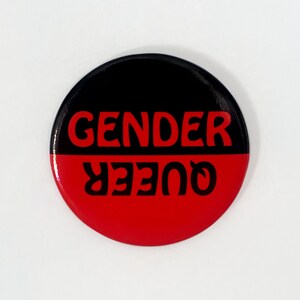 May include: A black and red button with the text "GENDER QUEER" in white letters.