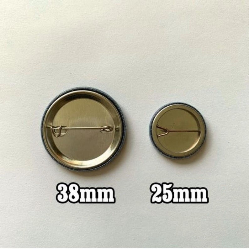 Peut inclure: Deux &eacute;pingles &agrave; bouton rondes en m&eacute;tal avec une finition argent&eacute;e. La plus grande &eacute;pingle mesure 38 mm de diam&egrave;tre et la plus petite 25 mm de diam&egrave;tre.