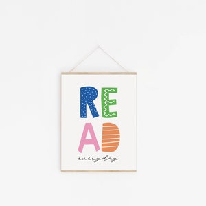 May include: A white framed print with the word "READ" in colorful, stylized letters. The letters are blue, green, pink, and orange. The text "everyday" is written in black script below the word "READ".