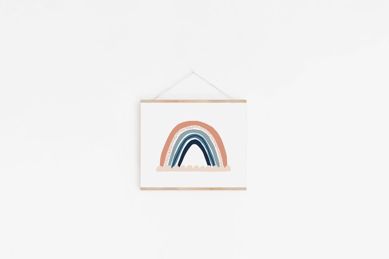 May include: A framed print of a rainbow with a peach, blue, and white color scheme. The rainbow is drawn in a simple, modern style with a white cloud underneath.