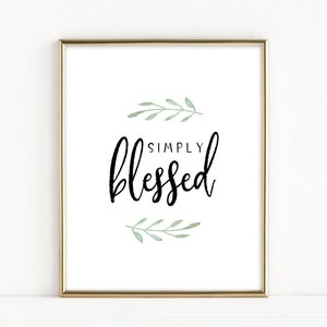 Puede incluir: Una impresión enmarcada en dorado con fondo blanco y texto negro que dice "SIMPLY blessed" con hojas verdes de acuarela arriba y abajo del texto.