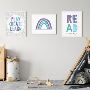Puede incluir: Tres impresiones enmarcadas con texto e ilustraciones coloridas cuelgan de una pared blanca en la habitaci&oacute;n de un ni&ntilde;o. Las impresiones presentan las palabras "Play Create Learn", un arco&iacute;ris y "Read everyday". Un tipi de madera con un interior de tela con estampado gris y negro se encuentra en primer plano.