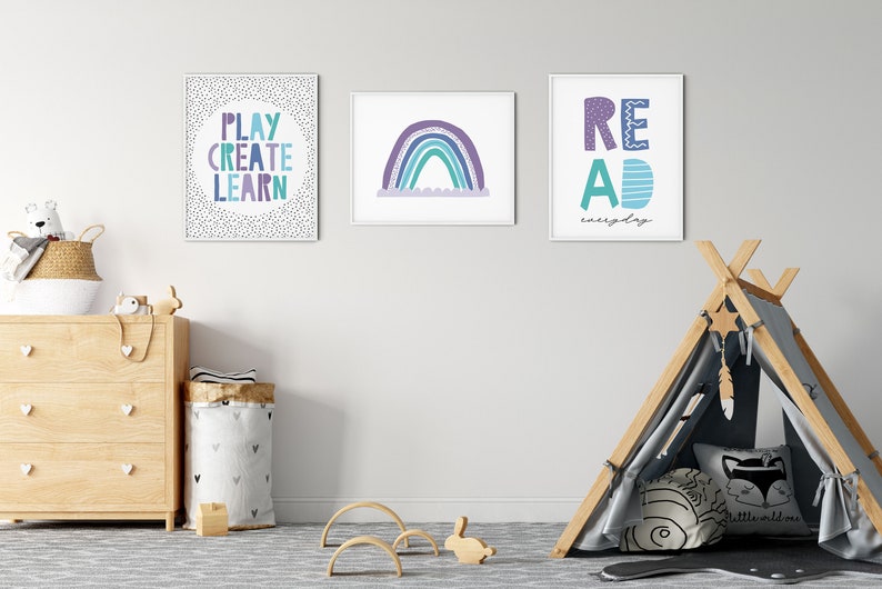 Puede incluir: Tres impresiones enmarcadas con texto e ilustraciones coloridas cuelgan de una pared blanca en la habitaci&oacute;n de un ni&ntilde;o. Las impresiones presentan las palabras "Play Create Learn", un arco&iacute;ris y "Read everyday". Un tipi de madera con un interior de tela con estampado gris y negro se encuentra en primer plano.
