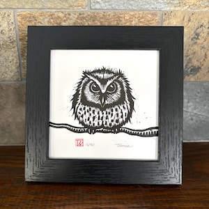 May include: Black and white owl art print in a black frame. The owl is perched on a branch, with intricate details in its feathers. The print is numbered 12/50 and signed by Tania.