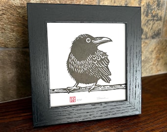 Round raven art in square frame. Original signed linocut raven.