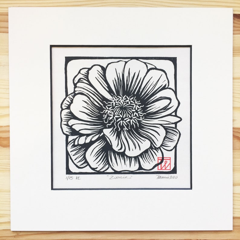 May include: Black and white linocut print of a single flower with the title "Zinnia" and the number "1/15" in the bottom left corner. The print is signed and dated "Tania 2020" in the bottom right corner.