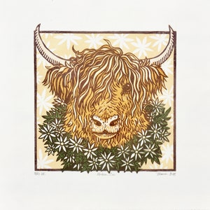 Puede incluir: Un primer plano de una vaca Highland con una corona de flores alrededor del cuello. La vaca es marr&oacute;n y blanca con un pelaje largo y peludo. Las flores son blancas con hojas verdes. El fondo es de color amarillo claro con un patr&oacute;n floral blanco.