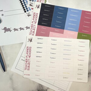 Op de afbeelding: Een set stickers voor een lerarenplanner met kleurrijke labels voor de dagen van de week. De stickers zijn bedrukt met een witte achtergrond en zwarte tekst. De stickers zijn gerangschikt in rijen en kolommen op een wit oppervlak.