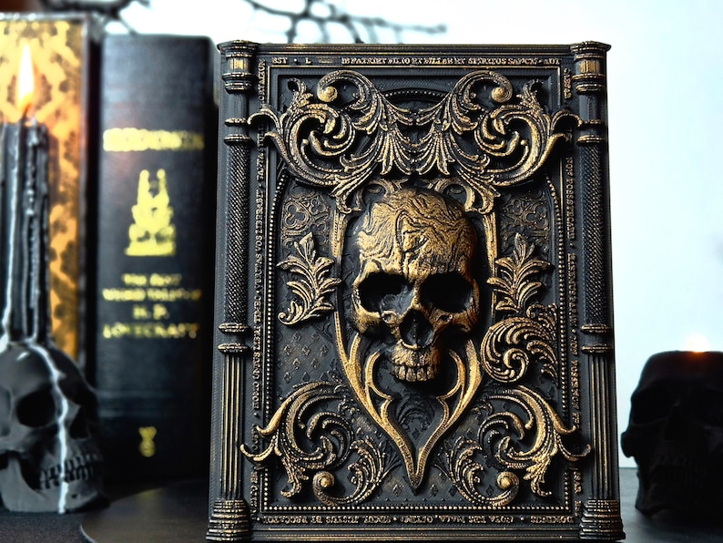 May include: A black book with gold accents and a skull design. The book is decorated with intricate floral patterns and has a gothic aesthetic.
