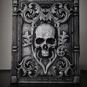 May include: A black and white decorative skull with ornate scrollwork and text around it. The text reads "DUBITO ER HOMO UNIUS LIBRI TIMBO VERITAS VOS LIBERABIT TANTAST CORTALIUM, BSTLIB PATRIET PILIO ET VILLAB ET SPIRITOS SANCIT AUT CABSAR FON POSSAFECARE HASEMUS PAPAX WON POSSENON PHO SAT H DOMINGS NOTA TBS MALA, OFTIMA SIMUL JUSTUS BT PECCATOR".