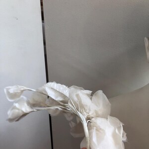 May include: A white silk flower with a delicate, layered design. The flower is made of multiple petals and has a long, thin stem.