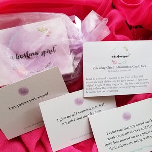 May include: Affirmation cards for grief release, featuring the text "a healing spirit". The cards include affirmations such as "I am patient with myself" and "I give myself permission to feel my grief." The cards are displayed on a pink fabric background.