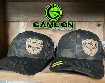 GAMEONGAMEOVER buck and bull SnapBack hat with a broad head puncture patch.