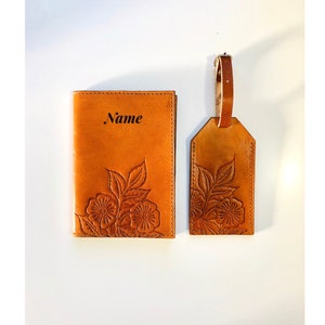 May include: A brown leather passport holder and luggage tag set with a floral design and the word "Name" embossed on the passport holder.