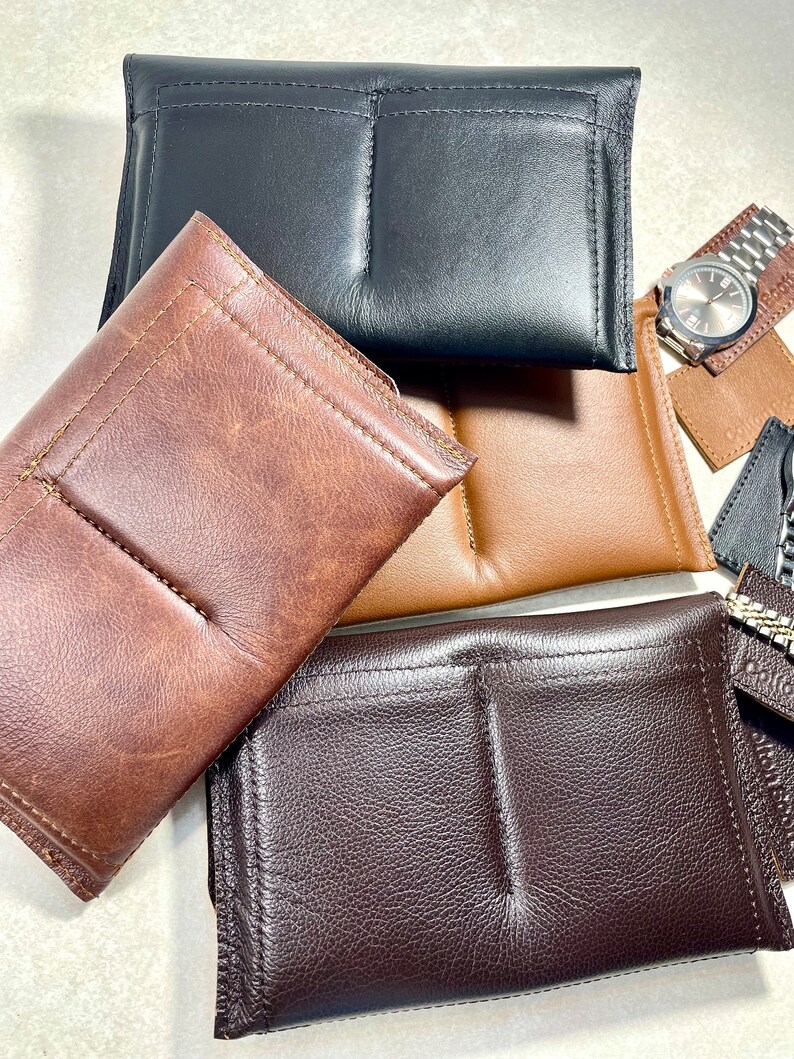 K&ouml;nnte beinhalten: Vier Uhrenboxen aus Leder in verschiedenen Farben: Braun, Schwarz, Dunkelbraun und Beige. Die Boxen haben zwei F&auml;cher zum Aufbewahren von Uhren.