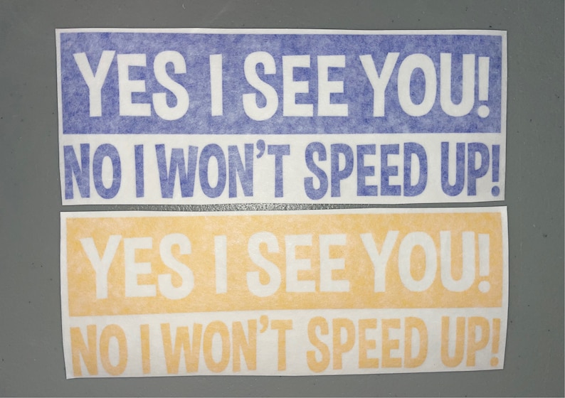 May include: Two rectangular bumper stickers with white text on colored backgrounds. The top sticker is blue with white text reading YES I SEE YOU! NO I WON'T SPEED UP! The bottom sticker is yellow with white text reading YES I SEE YOU! NO I WON'T SPEED UP!