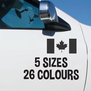May include: A black Canadian flag decal on a white car door. The decal features the maple leaf emblem and the text "5 SIZES 26 COLOURS" in black. The car's wing mirror is visible in the image.