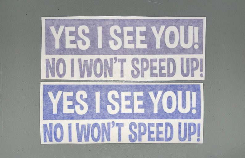 May include: Two rectangular bumper stickers featuring white text on a purple background. The text on both stickers reads: YES I SEE YOU! NO I WON'T SPEED UP! The stickers are arranged one above the other, displaying the same message clearly.
