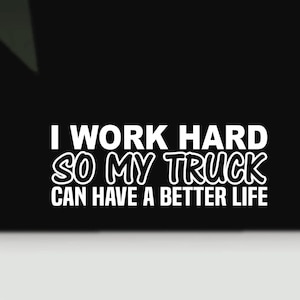 May include: A white vinyl decal sticker featuring the text I WORK HARD SO MY TRUCK CAN HAVE A BETTER LIFE in a bold, sans-serif font. The lettering is arranged in four lines against a solid black background, creating a high-contrast graphic design.