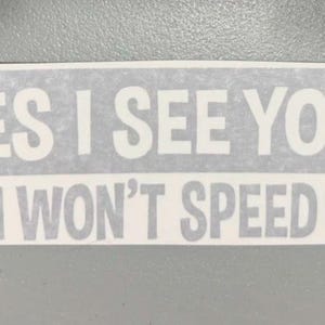 May include: A rectangular white vinyl decal featuring bold, sans-serif lettering in two lines. The top line reads YES I SEE YOU! and the bottom line reads NO I WON'T SPEED UP! The text is presented in a clear, high-contrast font style.