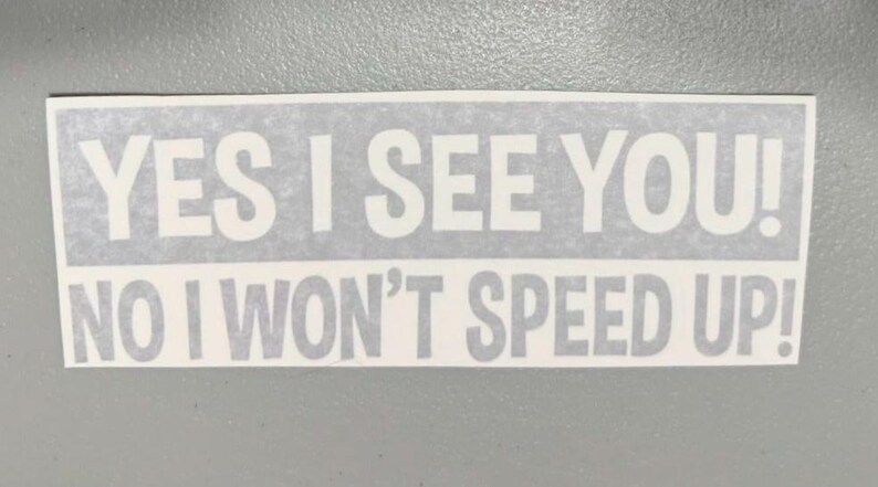 May include: A rectangular white vinyl decal featuring bold, sans-serif lettering in two lines. The top line reads YES I SEE YOU! and the bottom line reads NO I WON'T SPEED UP! The text is presented in a clear, high-contrast font style.