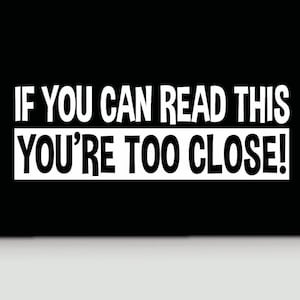 May include: Black and white sign with the text "IF YOU CAN READ THIS YOU'RE TOO CLOSE!"