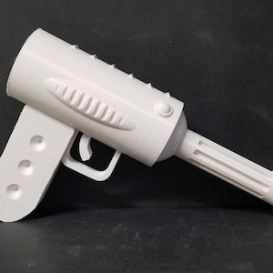 May include: A white plastic toy gun with a textured barrel and a handle with four holes. The gun has a trigger and a safety.