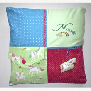 Könnte beinhalten: Ein grünes, blaues und pinkfarbenes Patchwork-Kissen mit einer Tasche und einem kleinen, befestigten Kissen. Das Kissen ist mit dem Namen "Mara" und einem Regenbogen bestickt.