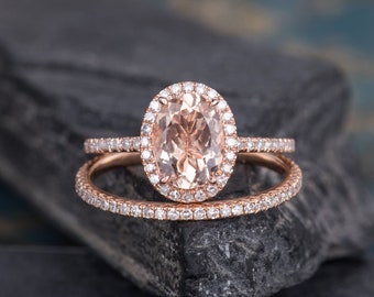 May include: A rose gold engagement ring set with a large oval-shaped morganite centre stone surrounded by a halo of smaller diamonds. The band is also set with smaller diamonds.