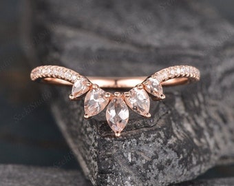 May include: Rose gold wedding band with a delicate curved design and five pear-shaped morganite gemstones. The band is accented with small round diamonds.