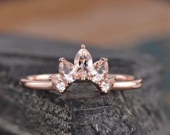 May include: Rose gold ring with a delicate, curved design featuring five pear-shaped morganite gemstones.