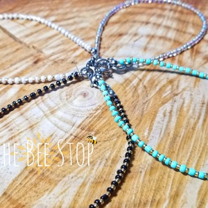 May include: Three beaded necklaces with gold and silver accents. The necklaces are white, black, and turquoise.
