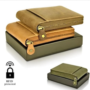 Puede incluir: Dos carteras de cuero color canela con cierres de cremallera y bolsillos externos apiladas sobre una caja oscura. Las carteras cuentan con cremalleras metálicas con tiradores de cuero. Un icono de candado con ondas de radio y el texto RFID protected es visible.