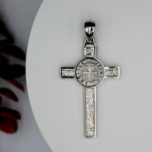 May include: Silver St. Christopher pendant with a detailed design. The pendant features a cross with a circular medallion in the center. The medallion has a detailed design of a saint and text around the edge.